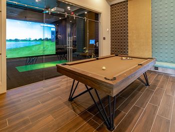 A pool table in a room with a glass wall and a television.